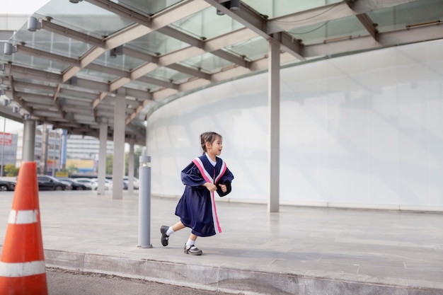 学校で卒業式の日に卒業式のガウンで幸せなアジアの女の子Graduation concept with copy spacex9