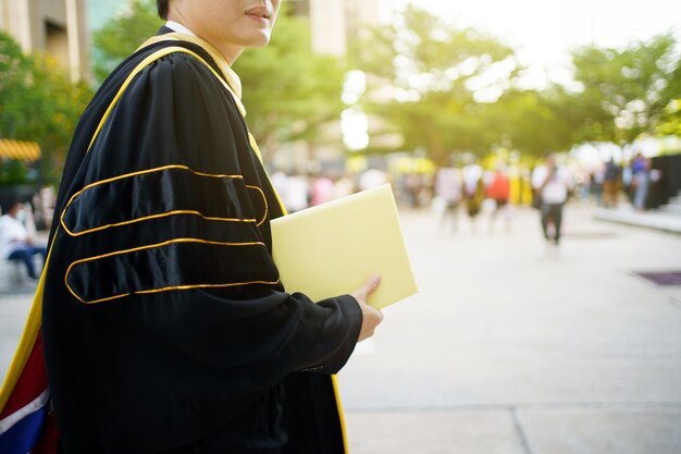 Happy asian graduate student holding the diplomas on hand
during the university graduation ceremony master degree student in
gown suit holding a diplomas for photography