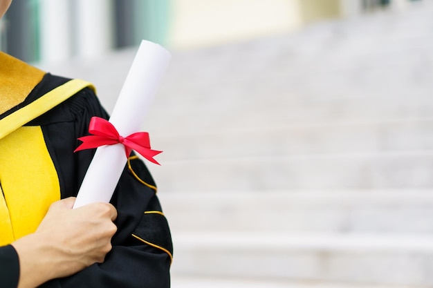 Happy asian graduate student holding the diplomas on hand
during the university graduation ceremony master degree student in
gown suit holding a diplomas for photography