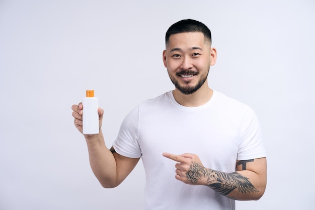 Happy asian handsome man wearing white t shirt holding cream