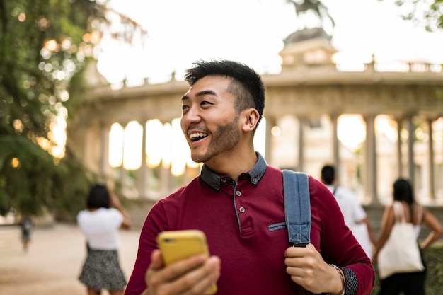 Happy asian japanese tourist visiting european city at sunset using smartphone to look at city map