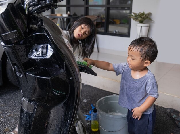 家でバイクのスクーターを遊んで洗う幸せなアジアの子供