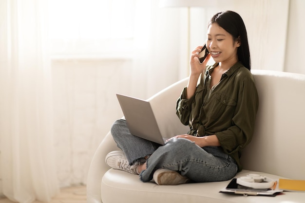 Happy asian lady freelancer working from home using laptop