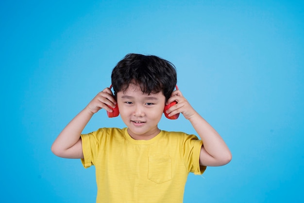 Счастливый азиатский маленький мальчик с наушниками слушает музыку