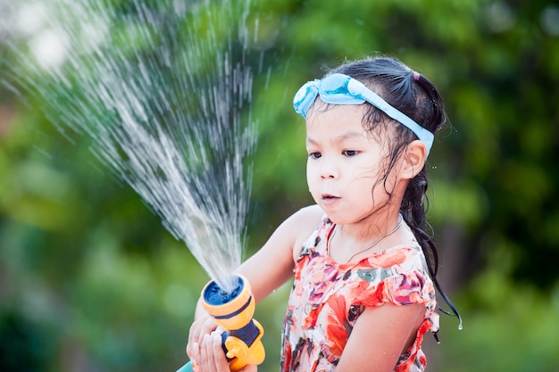 Happy asian little child girl wearing swimming goggles having fun to play water in summer 