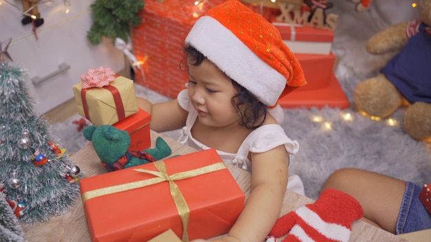 Happy Asian little girl have fun on Christmas day. Kid with parent with Christmas tree decoration at home on holiday.