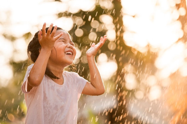 Happy asian little girl having fun with the water