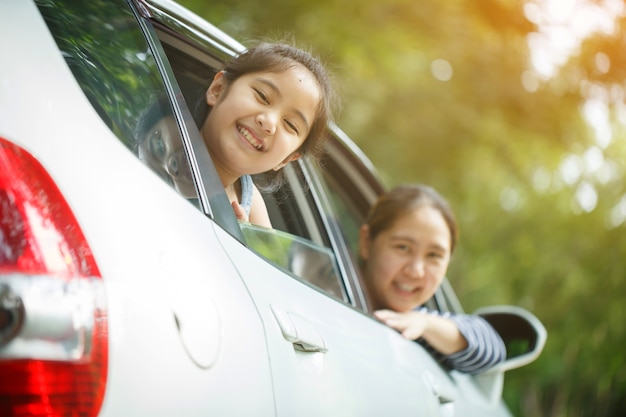 Bambina asiatica felice che gioca sull'automobile della finestra