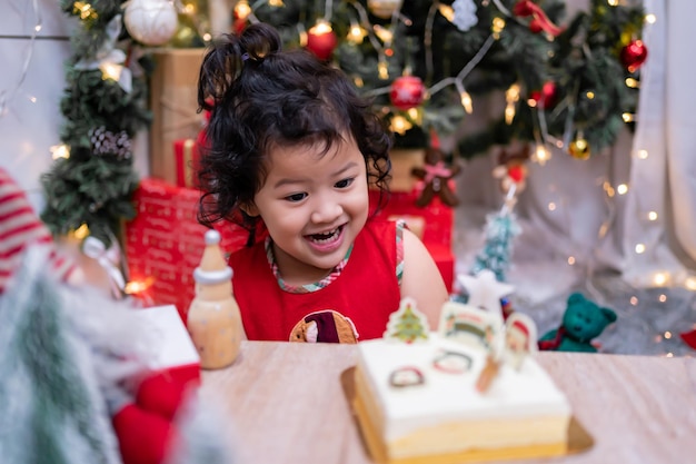 家族との冬の休日に家でクリスマスケーキと幸せなアジアの少女。