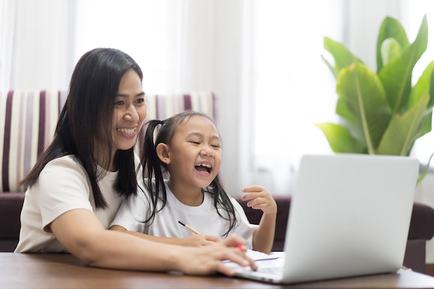 Happy asian little girl with mother using laptop computer, Study From Home idea concept