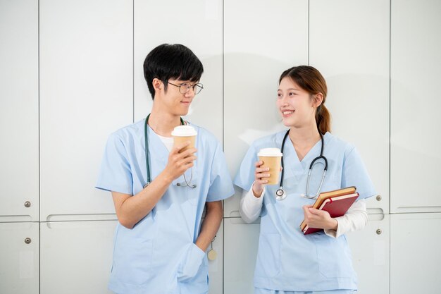 Photo happy asian male and female doctors are enjoying a conversation and hot drinks in the locker room