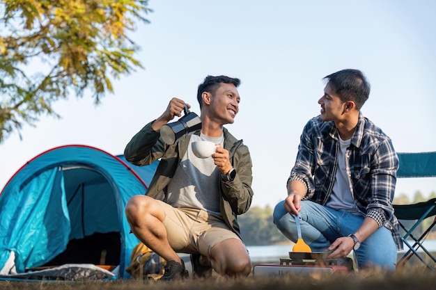 Happy Asian male gay couple on camping together in a forest romantic vocation trip lgbt concept