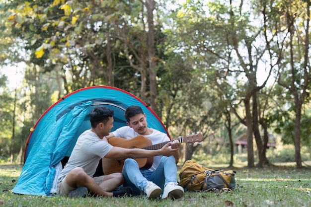 Happy Asian male gay couple on camping together in a forest romantic vocation trip lgbt concept