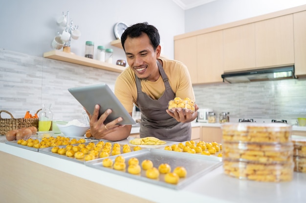 若い男の幸せなアジア人男性の自家製ケーキの肖像画は、プラスチック容器の箱にnastarケーキを置きます