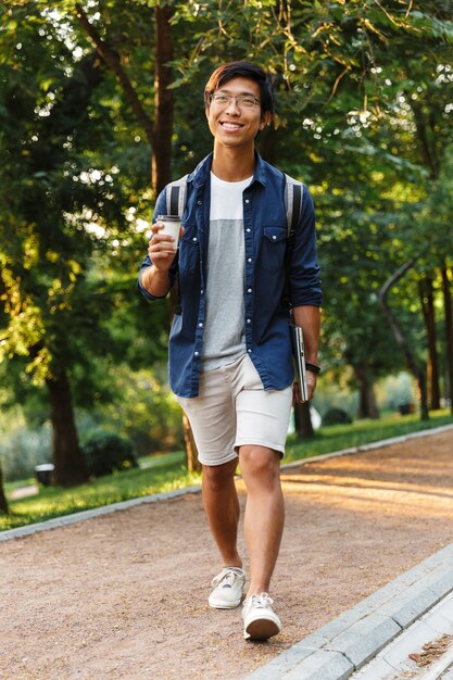 Premium Photo | Happy asian male student in eyeglasses walking with ...