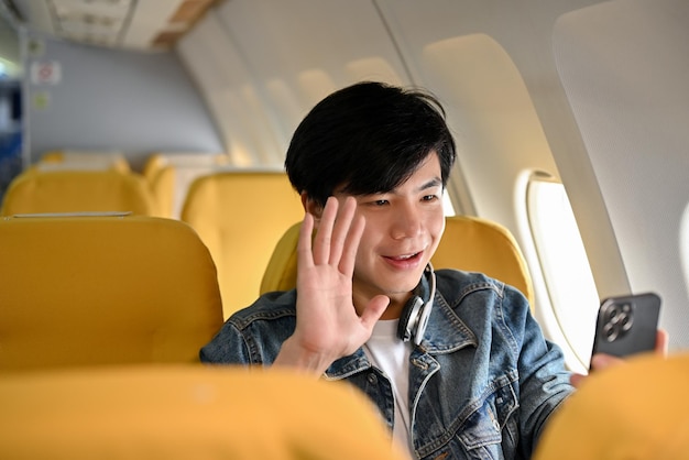 Photo happy asian male traveler passenger video calling after landing at his destination