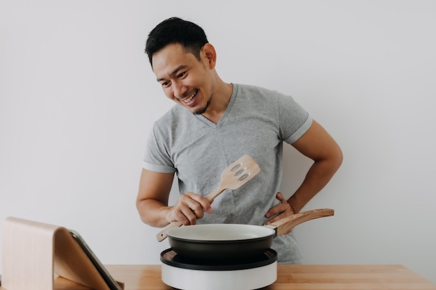 Happy asian man cooking online class with tablet isolated on white background