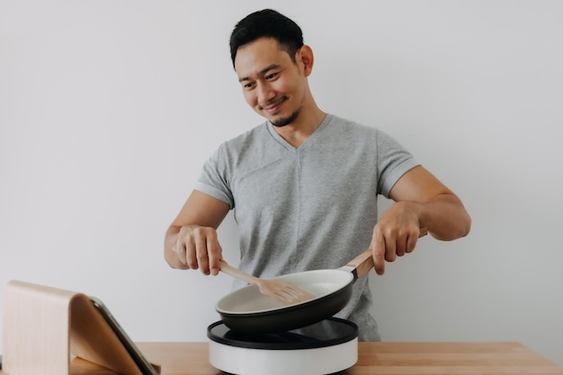 흰색 배경에 격리된 태블릿으로 온라인 수업을 요리하는 행복한 아시아 남자