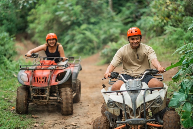 Happy asian man fastly riding the atv through the atv track leaving his partner behind