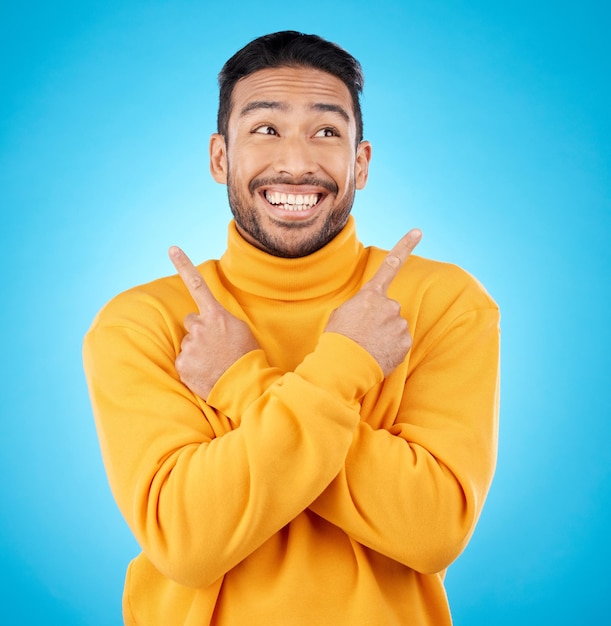 Happy asian man and hands pointing in studio for choice deal or sign up decision on blue background Smile direction and Japanese guy with recommendation suggestion or coming soon launch platform