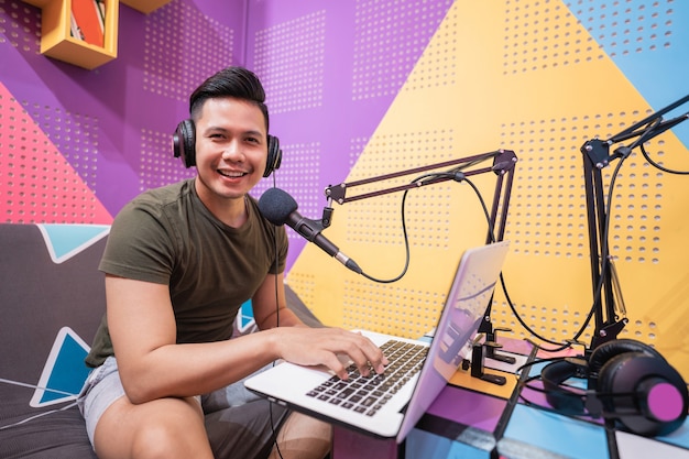 Happy asian man is recording a podcast in his studio