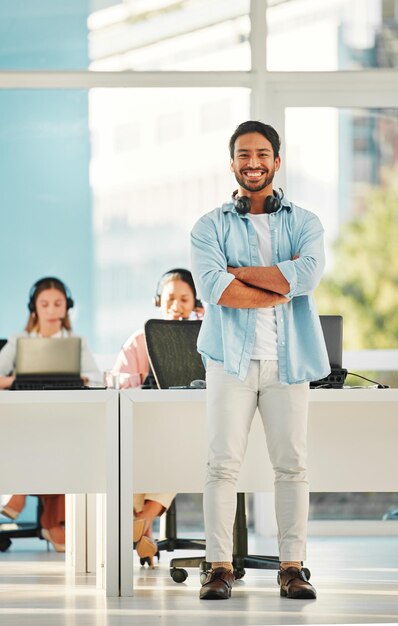 Photo happy asian man portrait and call center with arms crossed in customer service management or leadership at office male person consultant or agent manager smile in confidence contact us or help