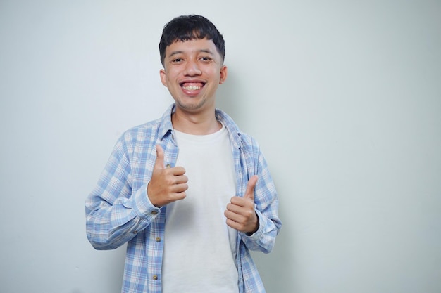 Happy asian man shows thumb up as a good hand sign isolated on white background