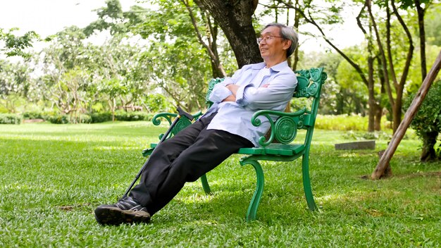 Happy asian man sitting on a bench at the park.