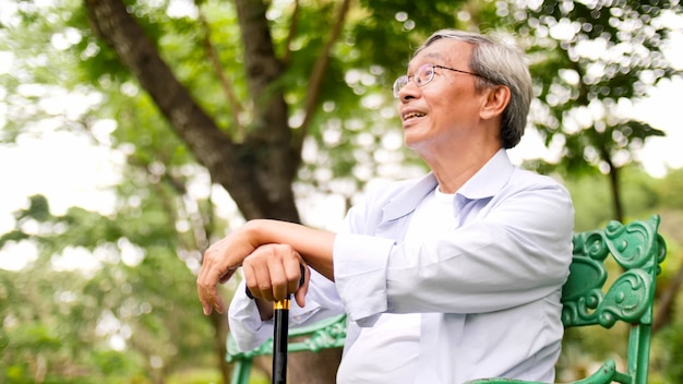 写真 公園のベンチに座って幸せなアジア男。