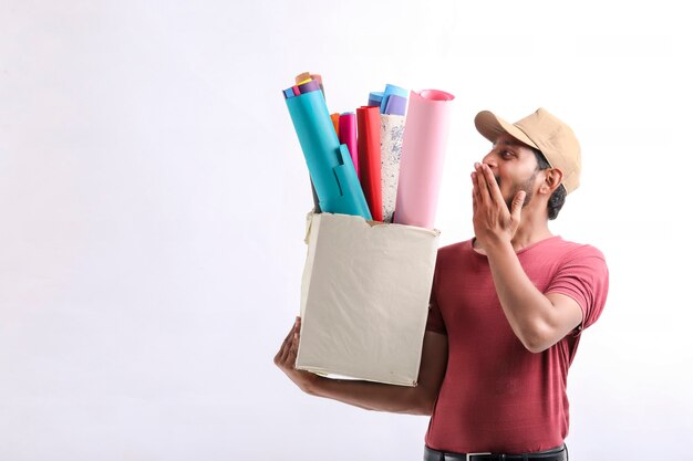 Happy Asian man in t-shirt and cap holding colour paper box isolated over white background, Delivery service concept