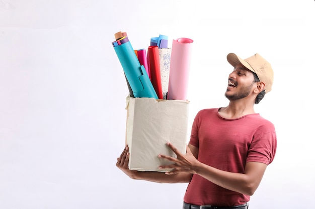 Happy Asian man in t-shirt and cap holding colour paper box isolated over white background, Delivery service concept