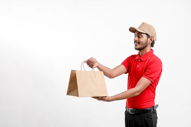 Uomo asiatico felice in maglietta e cappuccio che tiene scatola vuota isolata su sfondo bianco, concetto di servizio di consegna