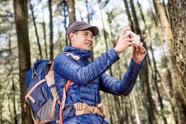 Happy asian man taking pictures of forest