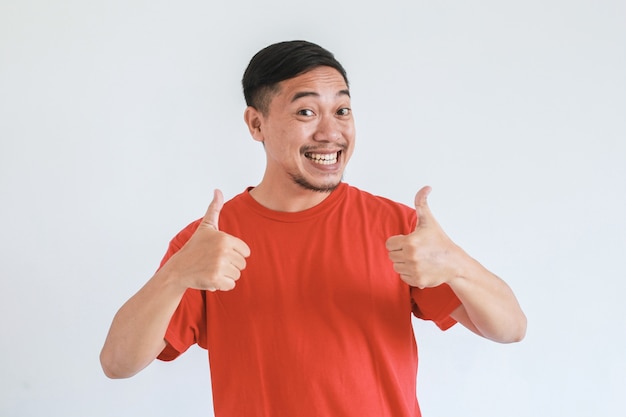 Happy Asian man wearing red t shirt with thumb up gesture on white background