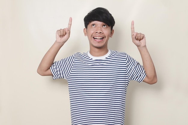 Happy Asian man wearing striped shirt pointing both hands up