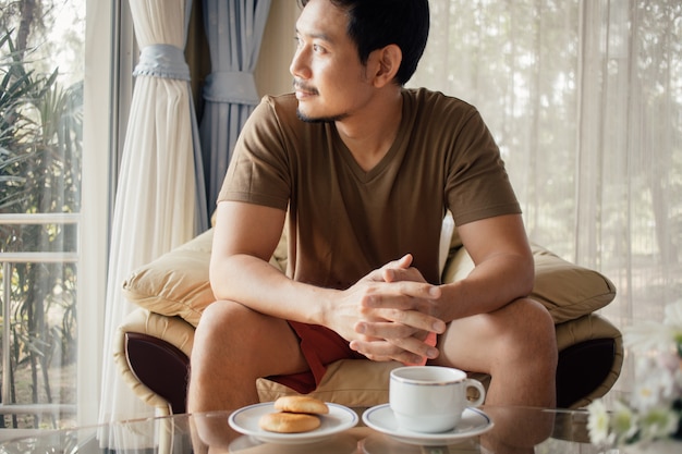 彼の朝食のコーヒーセットを持つ幸せなアジア人。