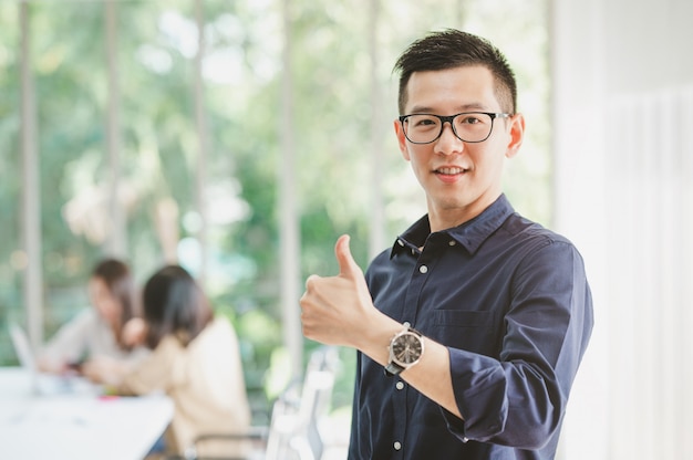 Happy Asian man with thumbs up with colleague