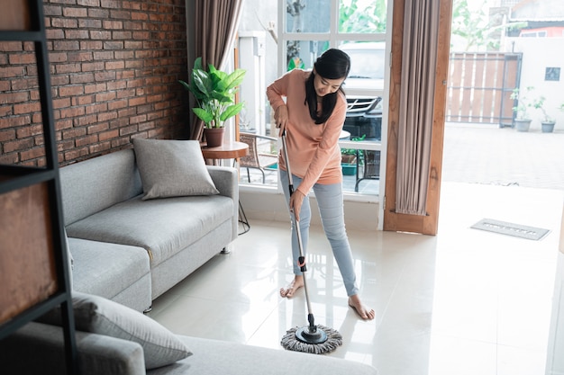 Happy asian mother cleaning the floor with mop