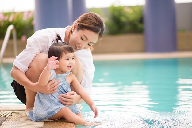 A Happy Asian mother and daughter are enjoy swimming in pool , lifestyle, parenthood, family concept