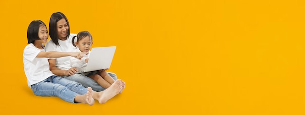 Felice madre e figlia asiatiche che utilizzano un banner lungo per laptop su sfondo giallo tracciati di ritaglio isolati per lavori di progettazione spazio vuoto vuoto mock up presentazione