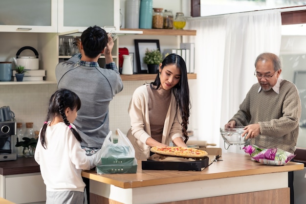 Happy asian multigenerational family setting up dining table.