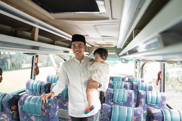Happy asian muslim man and daughter doing eid mubarak traveling back to his hometown by riding a bus