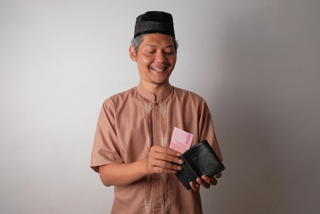 Photo happy asian muslim man holding indonesian money and wallet