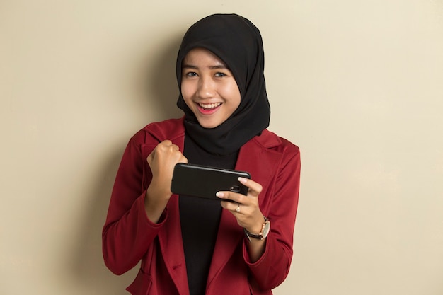 행복 한 아시아 이슬람 여자는 그녀의 스마트 폰에서 게임을 기쁘게 생각합니다.