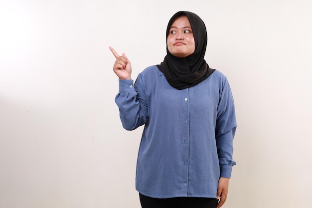 Happy asian muslim woman standing while pointing sideways