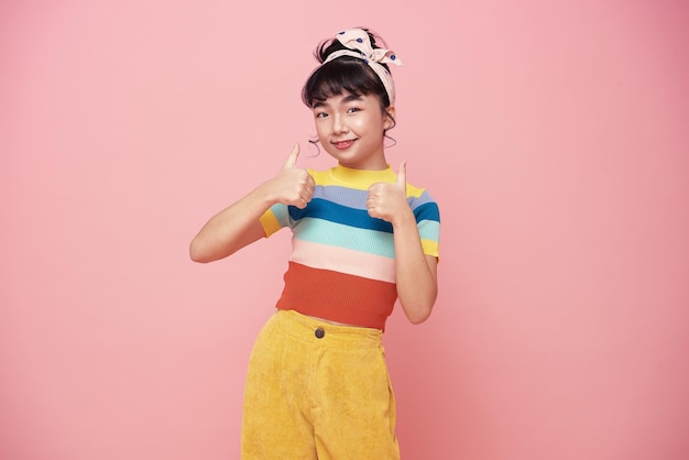 Happy Asian nice positive girl show two hands thumbs up have good mood isolated on pink background