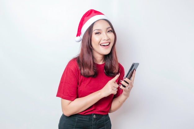 Happy Asian Santa woman is smiling and holding her phone isolated by white background Christmas concept