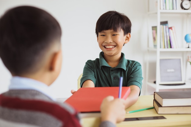 교실에서 상호 작용하는 행복한 아시아 학교 소년