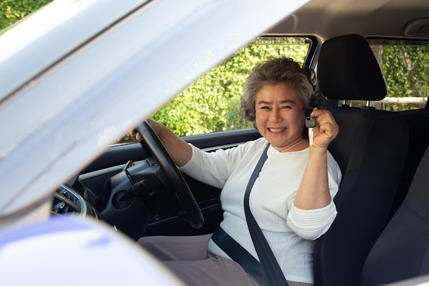 Happy Asian senior woman driver showing new car key.