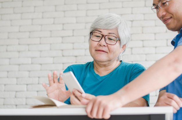 Foto donna senior asiatica felice che impara usare smartphone